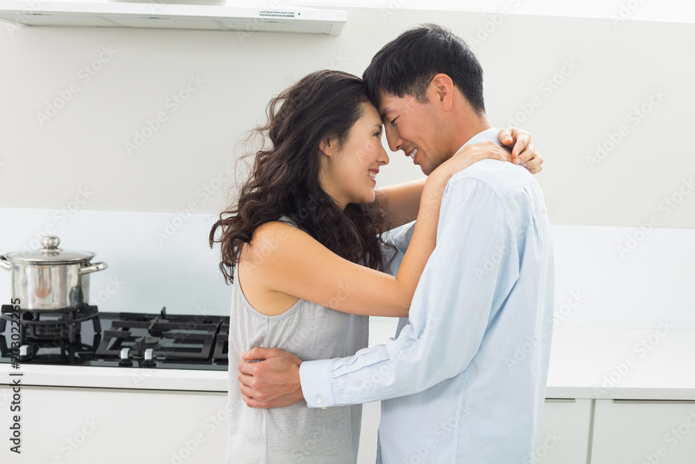 Side view of a man embracing woman in kitchen Side view of a man embracing woman in kitchen