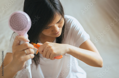 Young asian woman after bath hairbrushing her hair with comb,Female drying her long hair with dryer