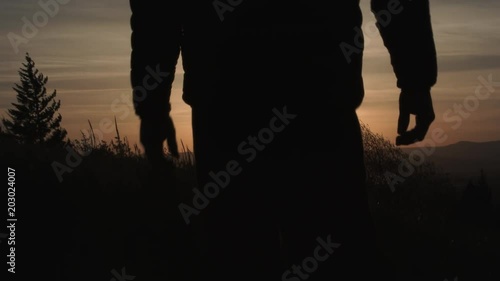 From black, transition to reveal person walking down grassy field in Oregon during sunrise, slow motion.