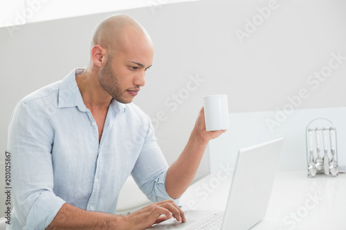 Concentrated casual man using laptop at home