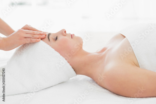 Hands massaging womans forehead at beauty spa