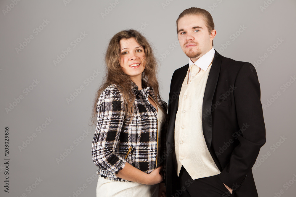 Elegant couple smiling for the camera while embracing. On grey background. Elegant couple smiling for the camera while embracing. On grey background.