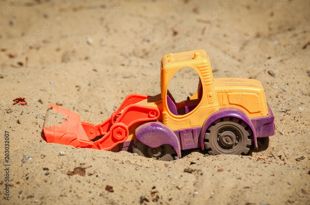 Toy Bulldozer in the sand. A small digger on the playground Toy Bulldozer in the sand. A small digger on the playground