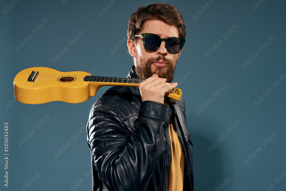 a man with glasses and a ukulele on a gray background