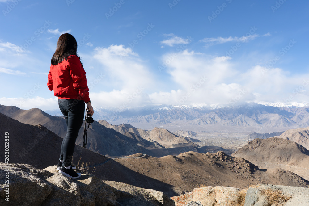 young traveler woman with canera at top of the mountain a breathtaking landscape Leh, Ladakh, North India, wanderlust travel concept, space for text, atmospheric epic moment