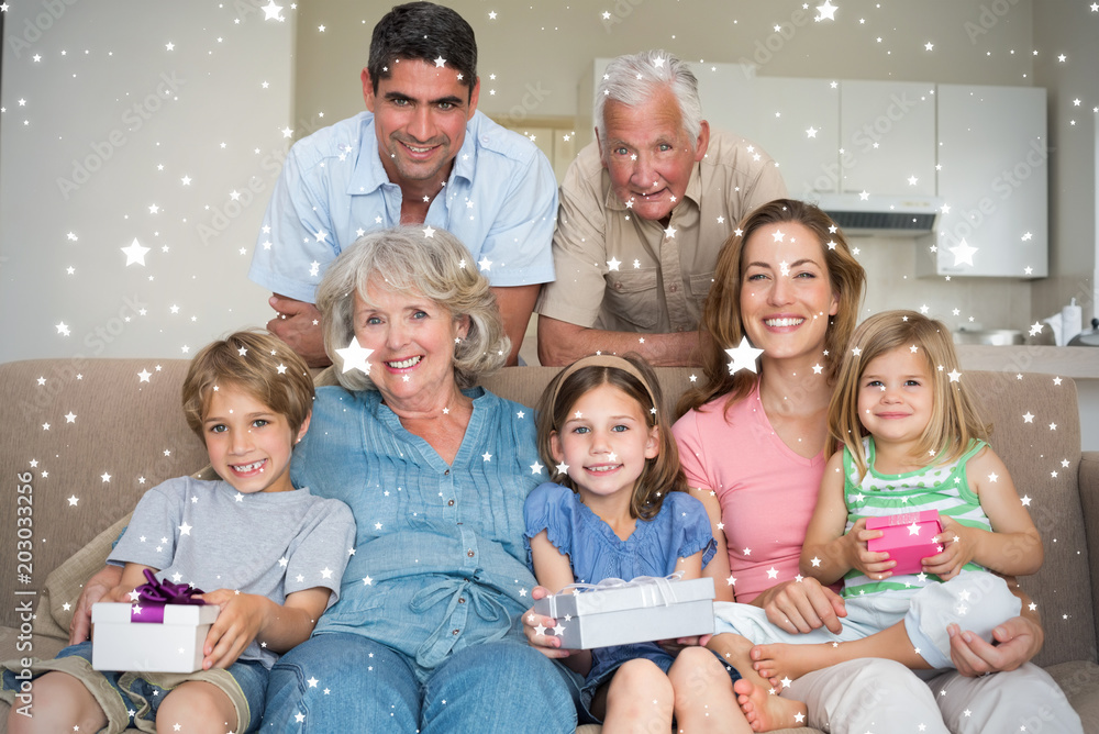 Composite image of Siblings holding gifts with family in living room against snow