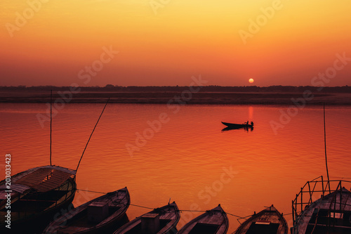 Orange Sunrise and Old style boats on Gang river, Varanasi photo