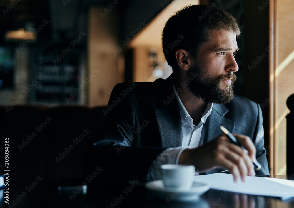 business man in suit and with pen in hand looking out the window