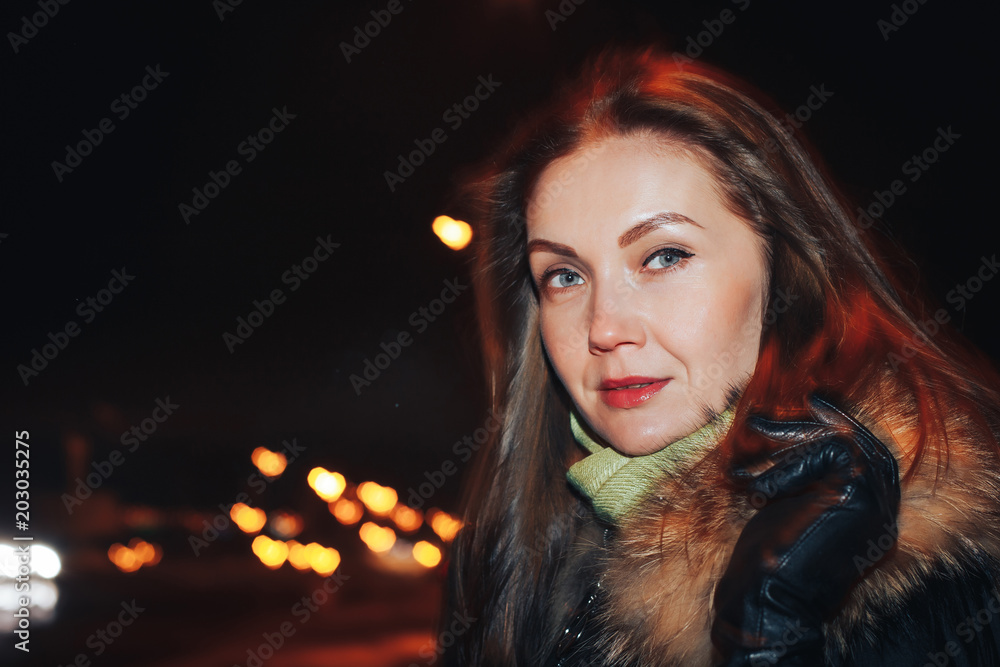 Naklejka premium Portrait of a nice girl in a warm coat in a dark city