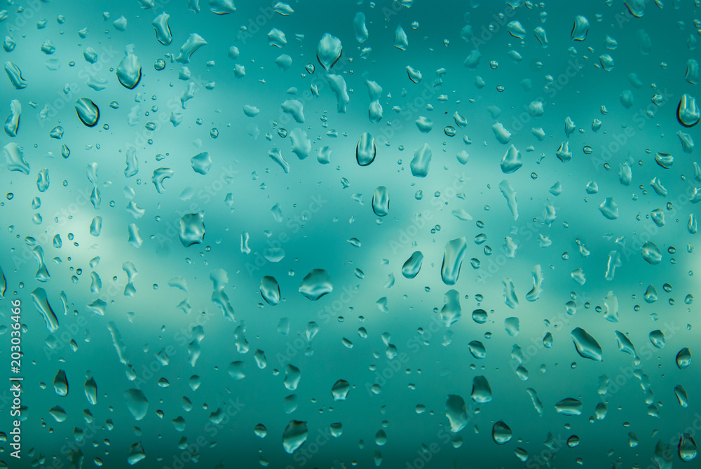 Blue water drops on window glass after rain. Cloud Background