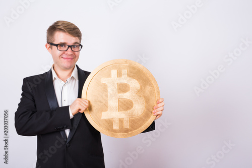 Businessnan holding big golden bitcoin on pink background. Crypto currency, virtual money, internet and economics concept photo