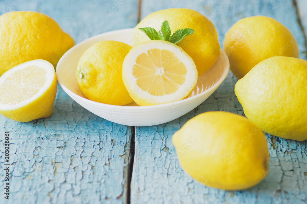 Yellow lemons with mint leaves, wooden background Yellow lemons with mint leaves, wooden background