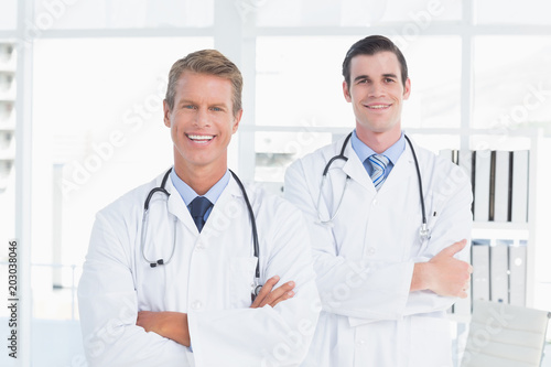 Smiling doctors looking at camera with arms crossed 