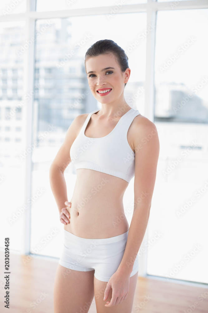 Content fit brown haired model in sportswear posing with a hand on the hip