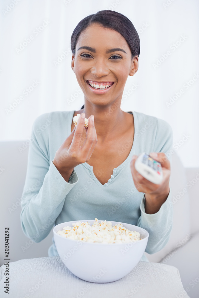 Cheerful attractive woman eating popcorn while watching tv Cheerful attractive woman eating popcorn while watching tv