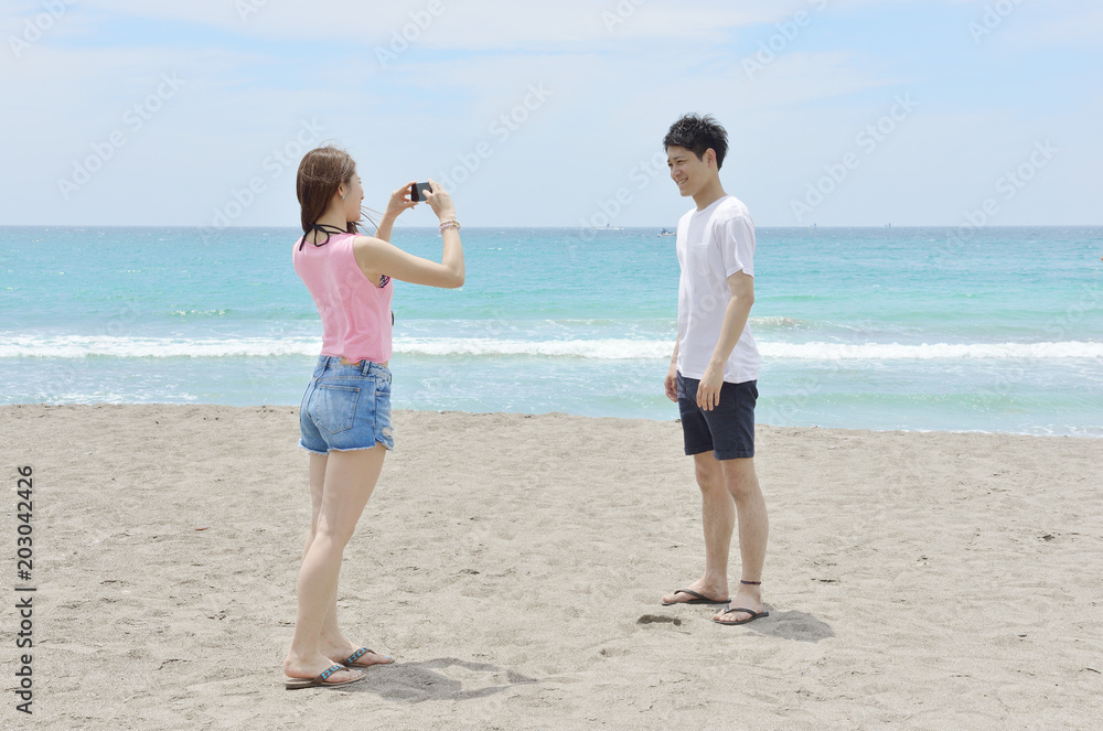 Fototapeta premium ビーチで写真を撮るカップル