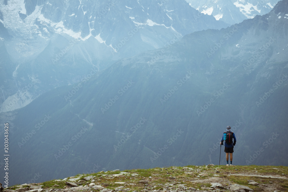 A hiker in the mountains, looking a the mountain range across a valley