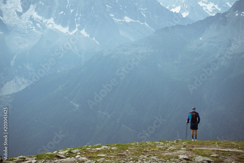 Fototapeta Naklejka Na Ścianę i Meble -  A hiker in the mountains, looking a the mountain range across a valley