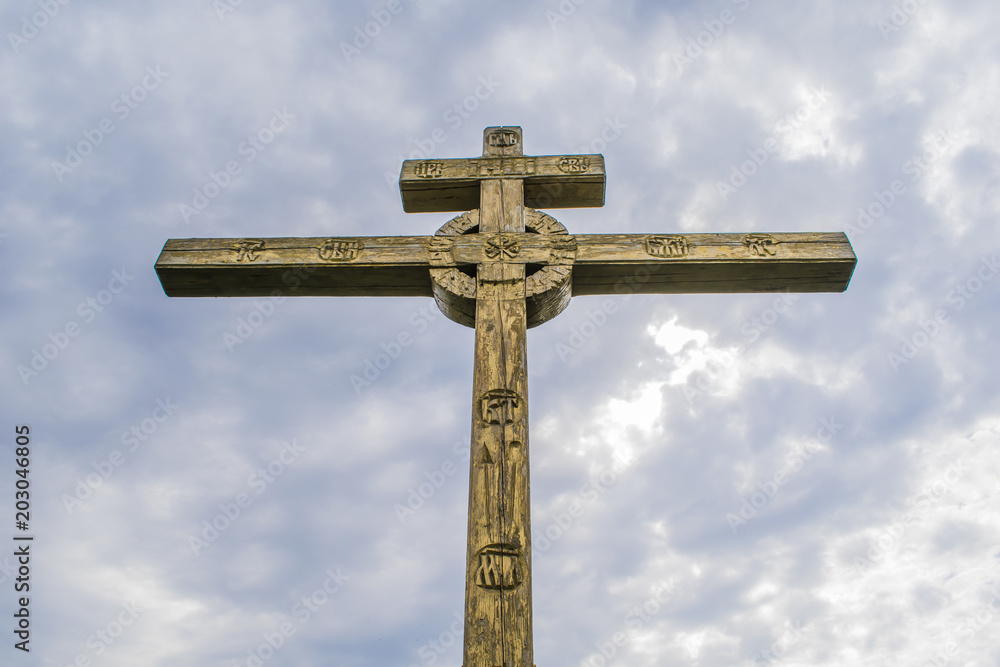 A wooden cross on top of a hill. Orthodox white cross glows on the top of the hill on the background of blue sky