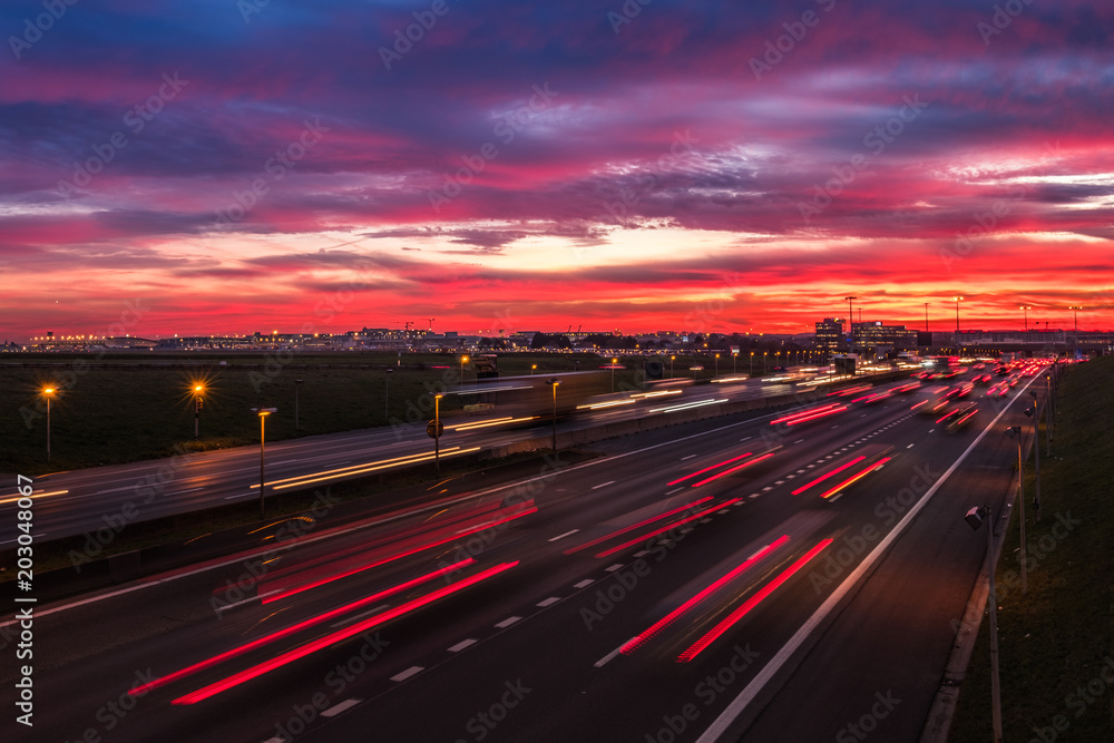 Dramatic sky at dawn with cars lights trails near the international airport of Brussels, Belgium