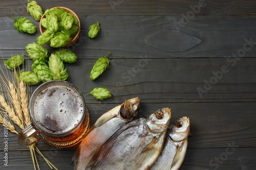 Glass beer with hop cones and dried fish on dark wooden background. Beer brewery concept. Beer background. top view photo