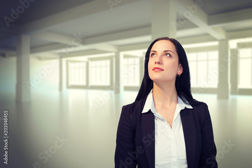 Pretty businesswoman looking up against white room with windows
