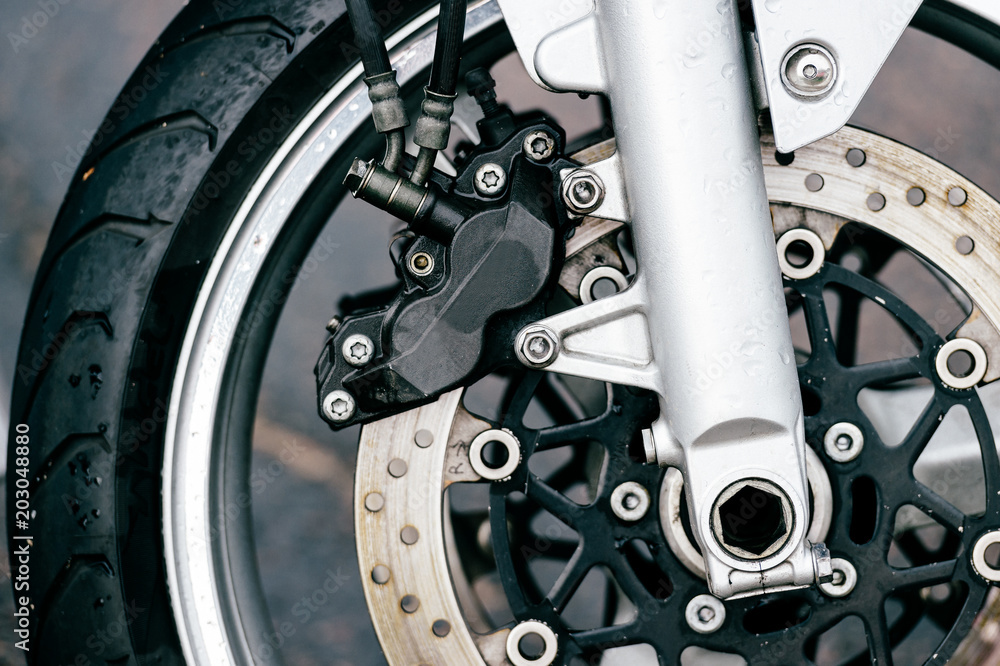 Motorcycle wheel with disk brakes system and metal spokes. Closeup detailed photo of motorbike forks and tire. Different parts of two-wheeled vehicle. Transportation. Modern driving technologies. Motorcycle wheel with disk brakes system and metal spokes. Closeup detailed photo of motorbike forks and tire. Different parts of two-wheeled vehicle. Transportation. Modern driving technologies.