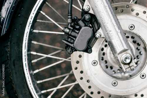 Motorcycle wheel with disk brakes system and metal spokes. Closeup detailed photo of motorbike forks and tire. Different parts of two-wheeled vehicle.  Transportation. Modern driving technologies. © benevolente