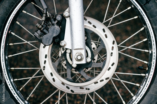 Motorcycle wheel with disk brakes system and metal spokes. Closeup detailed photo of motorbike forks and tire. Different parts of two-wheeled vehicle. Transportation. Modern driving technologies.