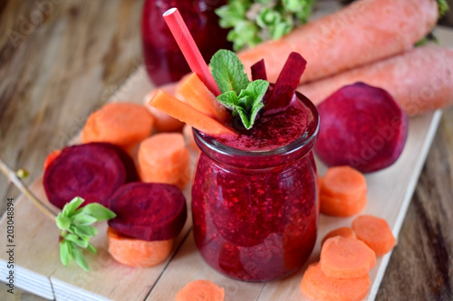 Foto Red smoothie made of carrot and beet is decorated with pieces of the vegetables