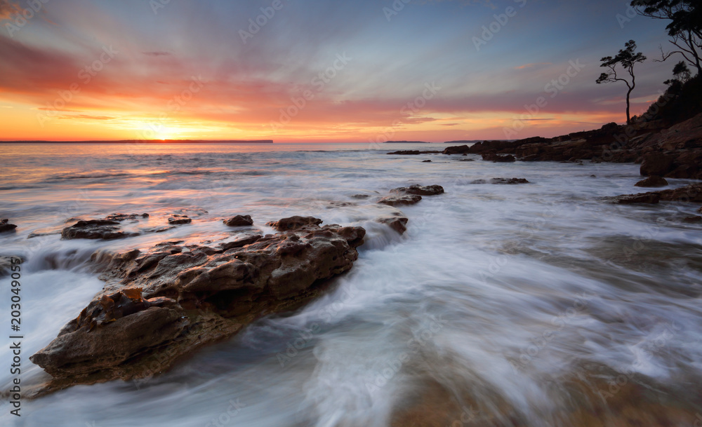 Sunrise over the Bay with ocean over rocks