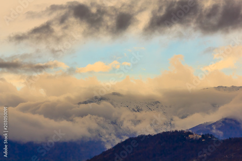 a snowy mountain surrounded by white and dark clouds /a landscape of striated clouds on a mountain