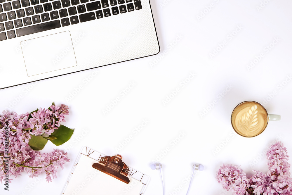 Feminine desktop close up of laptop computer keyboard, coffee cup & lilac flowers. Flat lay composition w/ notebook, blank sheet clipboard, earphone, purple bouquet. Background, flat lay, copy space. Feminine desktop close up of laptop computer keyboard, coffee cup & lilac flowers. Flat lay composition w/ notebook, blank sheet clipboard, earphone, purple bouquet. Background, flat lay, copy space.
