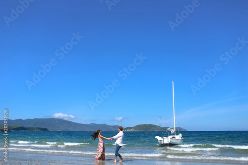 Young couple enjoying together spinning in a circle on the beach. Couple enjoying a summer vacation..