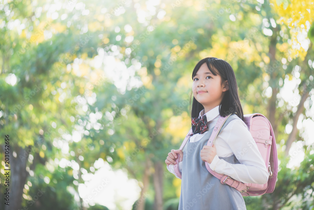 Asian school girl with pink backpack looking up outdoors,back to school concept Asian school girl with pink backpack looking up outdoors,back to school concept