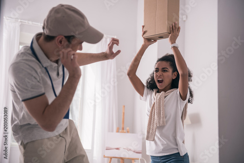 Bad service. Unhappy emotional woman shouting at the delivery man while showing her discontent with the order