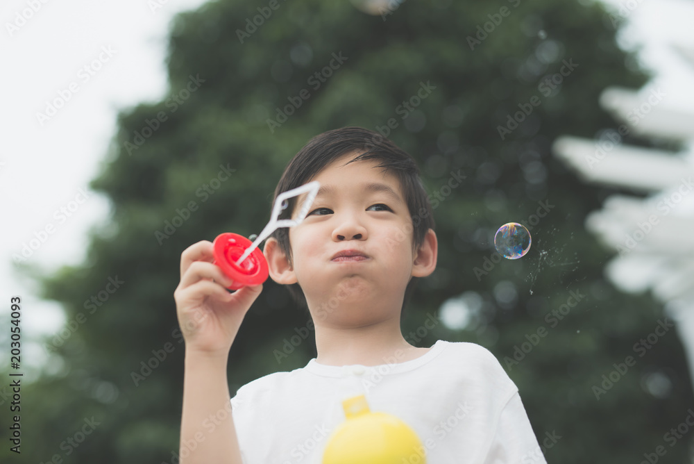 asian child is blowing a soap bubbles