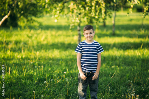 Little boy in a striped t-shirt looks through binoculars .Spring, sunny weather © Aleksandr