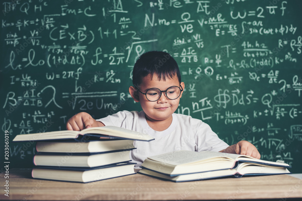 boy reading a book sitting at the table in the classroom