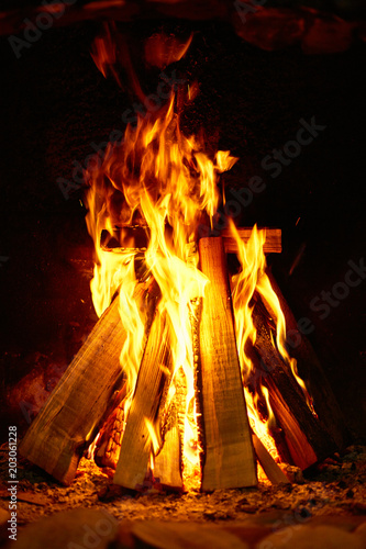 Burning firewood in the fireplace on a dark background.