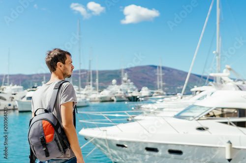 Young tourist looking at beautiful marina with luxurious yachts