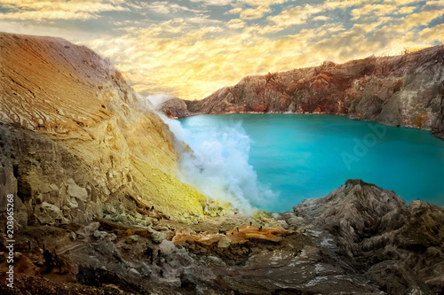 Yellow sulfur rocks and the blue sulfur lake of the crater of the Ijen volcano at dawn. Poisonous sulfur smoke. Mountain volcanic landscape.