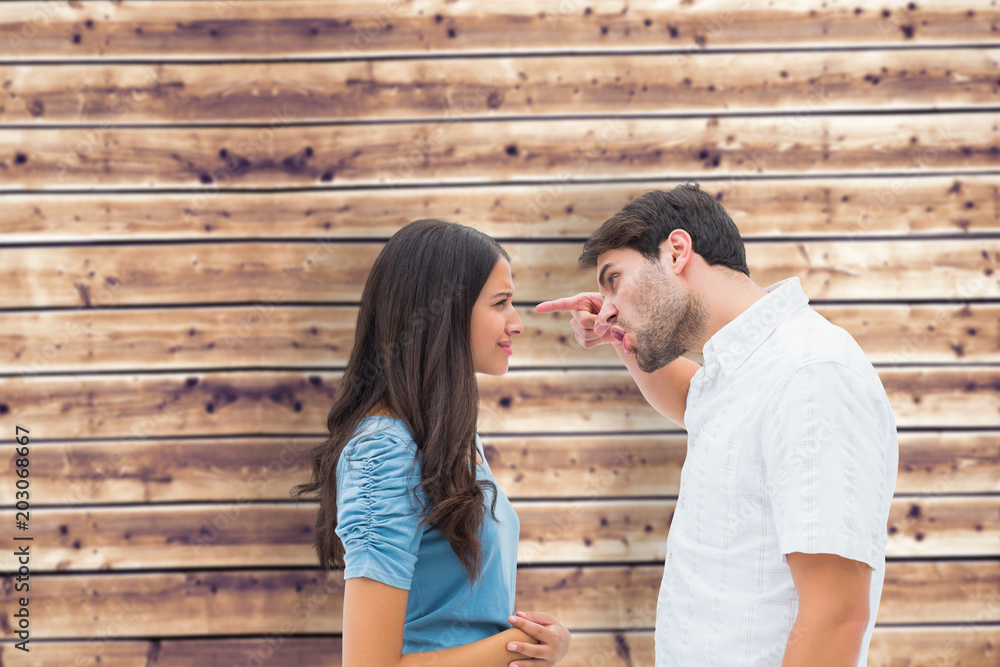 Angry man shouting at upset girlfriend against wooden planks background