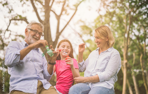 happy family in green nature park on summer ,grandfather blow soap bubbles along with grandchildren © saksit