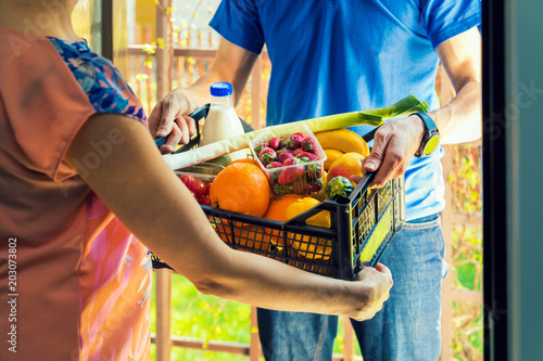 woman accepting groceries box from delivery man at home