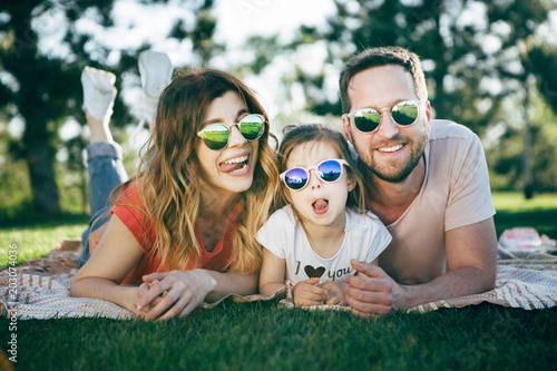 Family with dauhter in sunglasses rest in park.