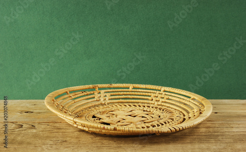 empty wicker basket on an old wooden table against grunge wall