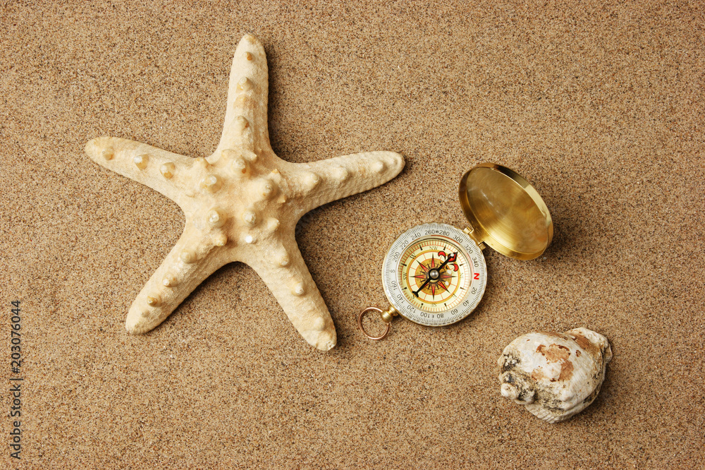 compass and starfish on a sandy beach compass and starfish on a sandy beach