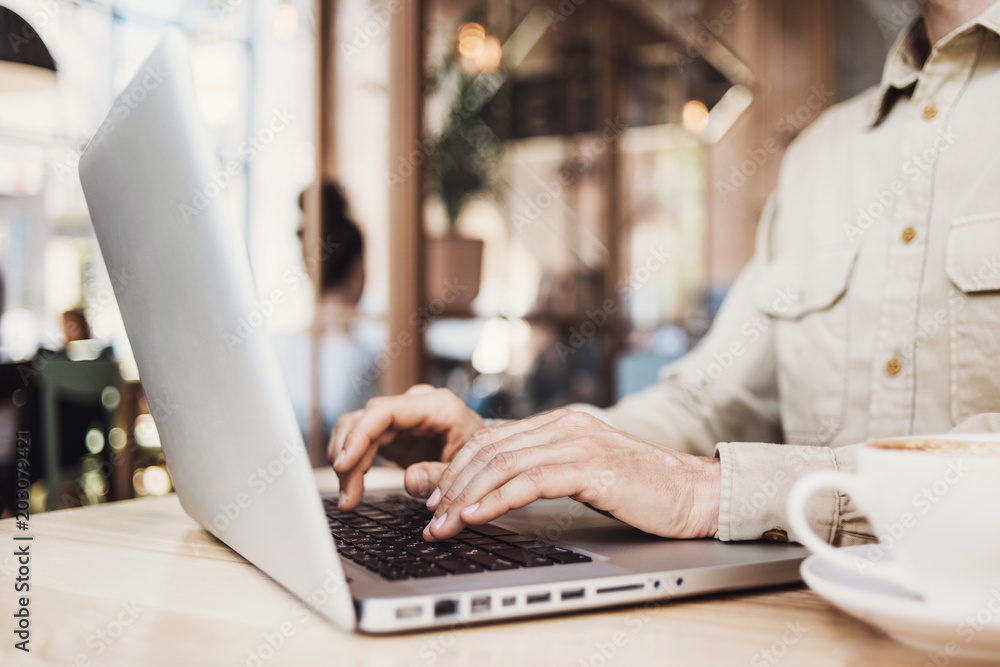 Closeup view of male hands working on laptop computer in a cafe.Online shopping, business and technology concept.Blurred background Closeup view of male hands working on laptop computer in a cafe.Online shopping, business and technology concept.Blurred background