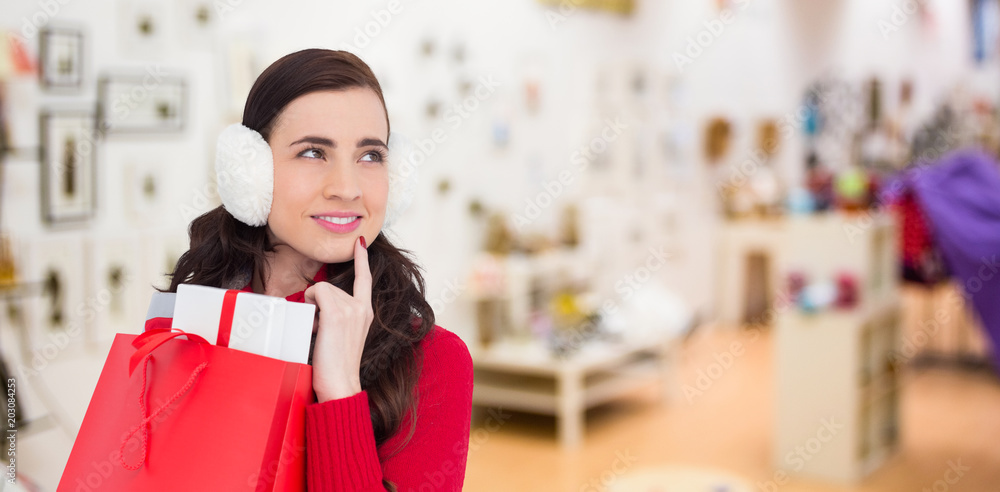 Brunette with ear muffs holding shopping bag full of gifts against furniture and design store Brunette with ear muffs holding shopping bag full of gifts against furniture and design store